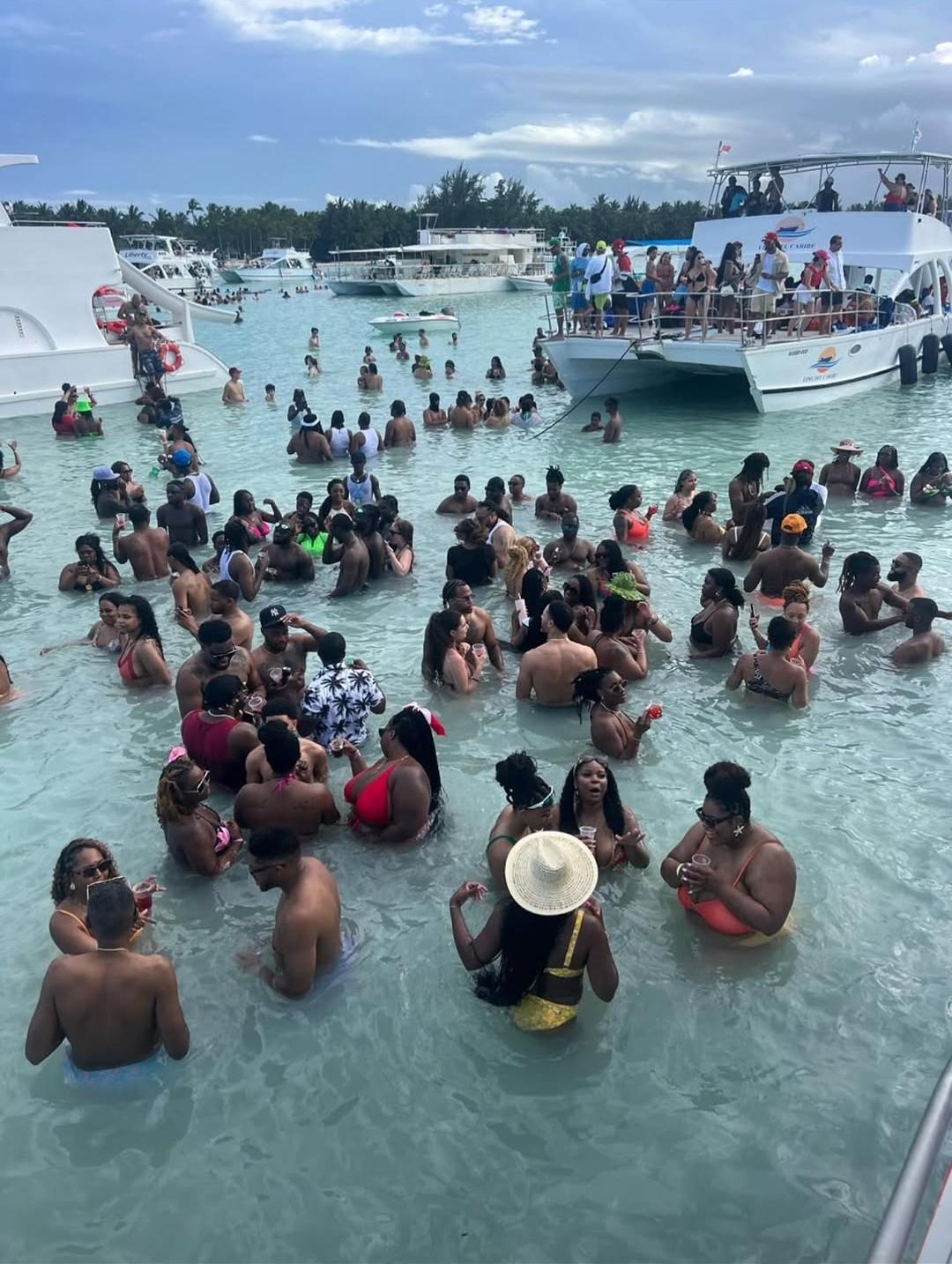 Travelers swimming beside Punta Cana party boats at a natural pool