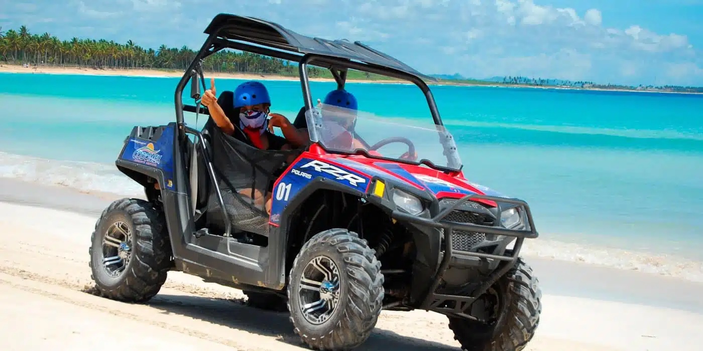 People driving dune buggies on a dirt path
