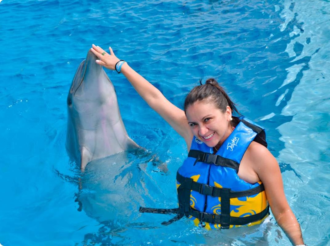 Person interacting closely with a dolphin in the water